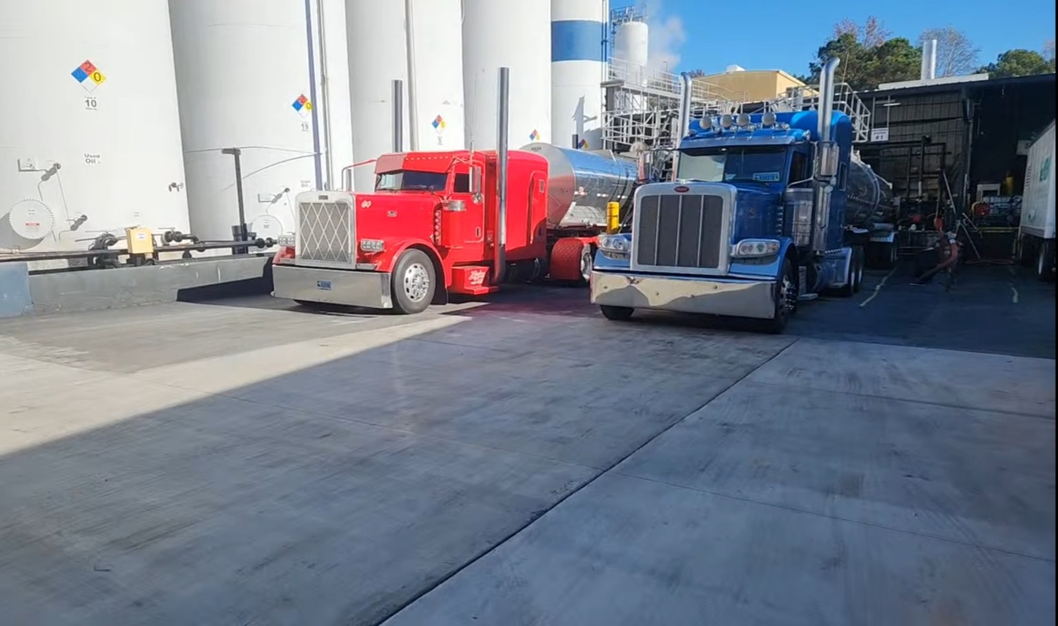 Red and blue Ziglar Transport tanker trucks loading at a facility